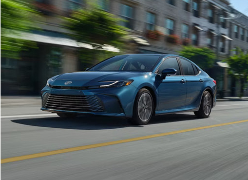 Blue Toyota Camry sedan driving through a city street with motion blur in the background