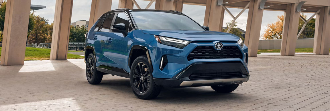 Blue Toyota RAV4 parked outdoors near modern architectural structure