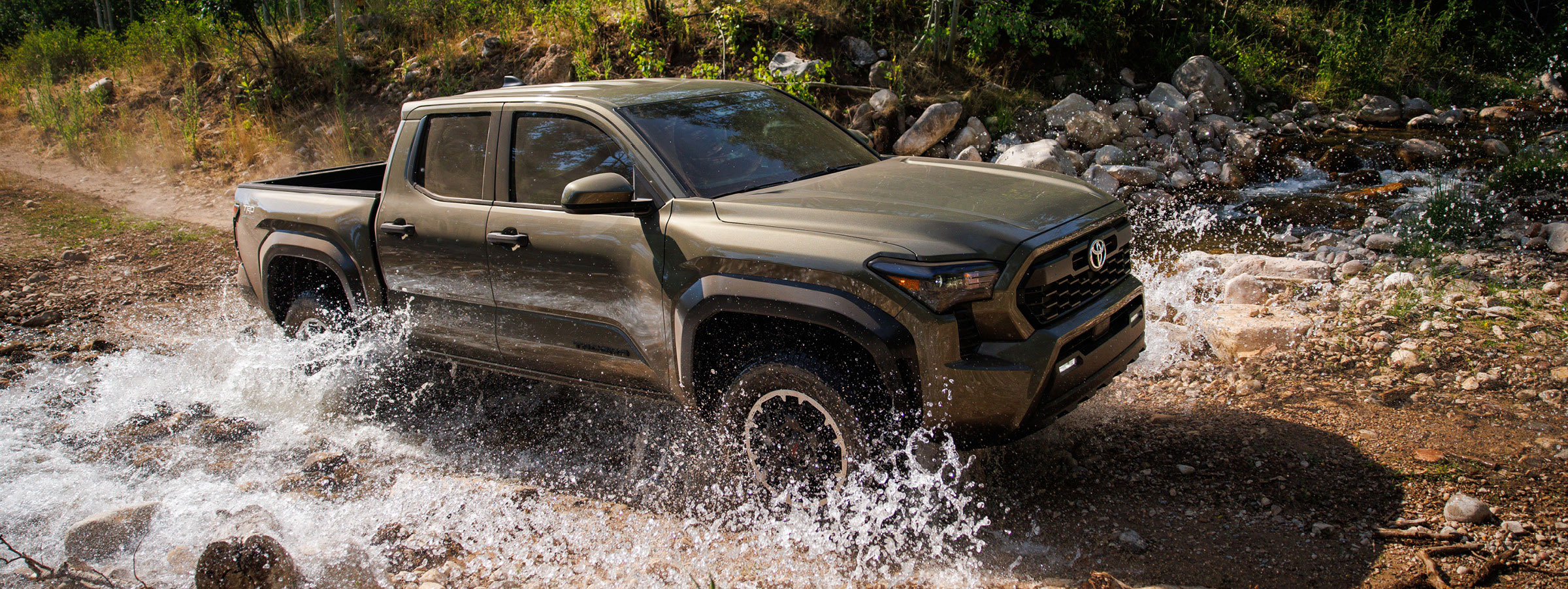 Toyota Tacoma TRD Off-Road pickup truck driving through a rocky stream