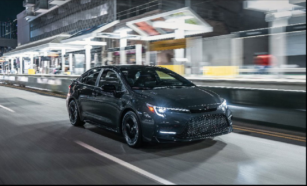 Toyota Corolla sedan driving at night on a city street