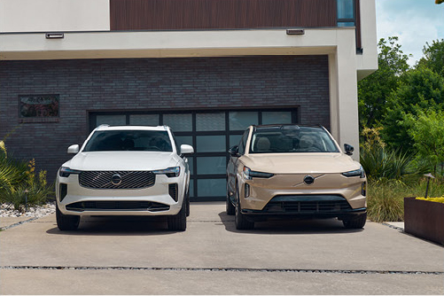 Two Volvo electric SUVs parked in front of modern home garage
