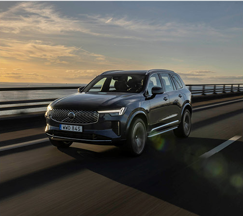 Volvo electric SUV driving on highway at sunset with modern Scandinavian design