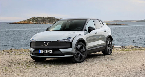 Volvo EX30 parked by the waterfront, emphasizing premium Scandinavian styling, all-electric performance, and everyday versatility