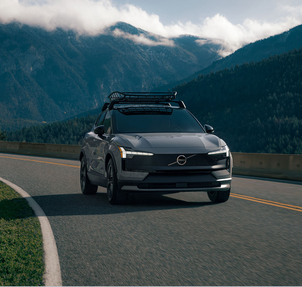 Volvo electric SUV driving on a mountain road with scenic landscape
