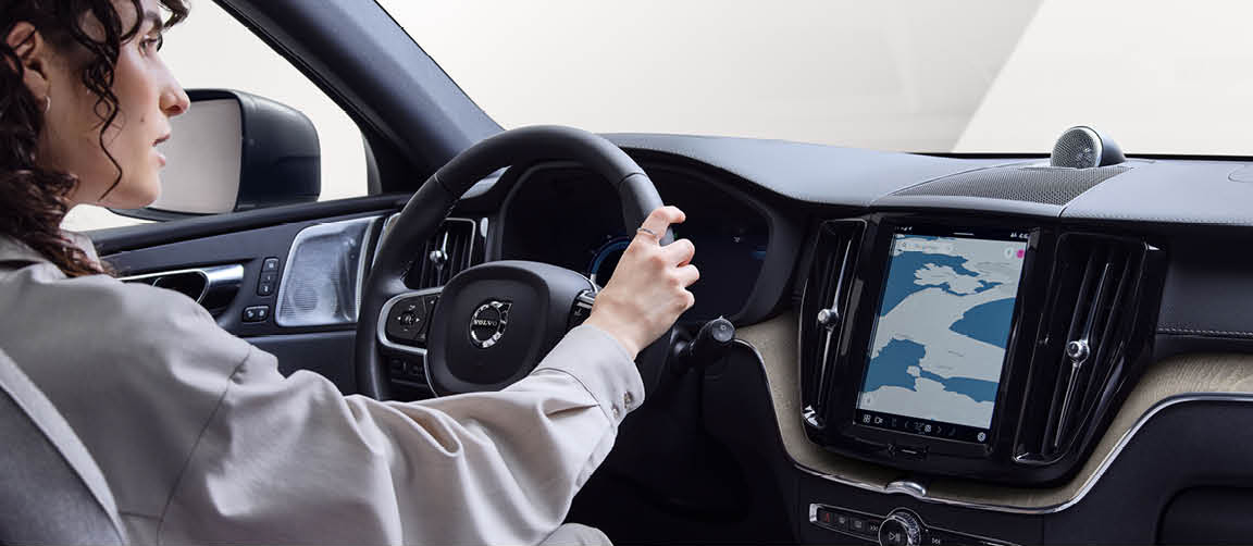 Driver using Volvo SUV interior with digital touchscreen navigation system