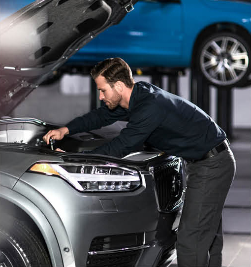 Technician performing maintenance under the hood of a Volvo XC90 SUV