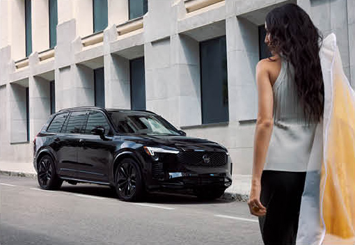 Volvo XC90 luxury SUV parked on a modern city street with pedestrian walking nearby