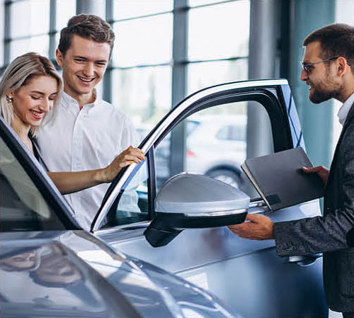 Couple reviewing vehicle features with sales consultant at dealership