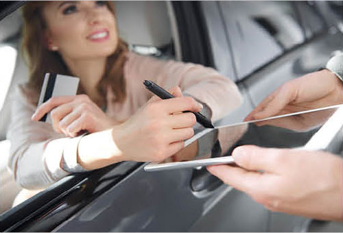 Customer signing car purchase agreement with dealership representative