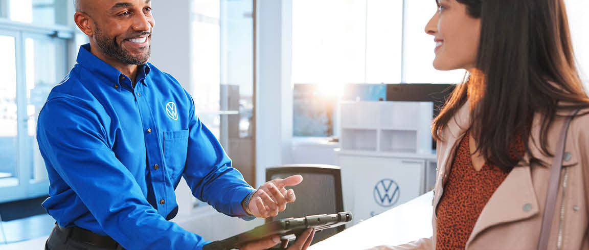 Volkswagen service advisor assisting customer at dealership service desk