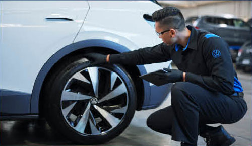 Volkswagen technician inspecting tire condition during vehicle service