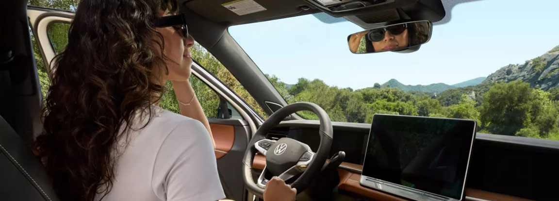 Driver using Volkswagen infotainment system inside modern vehicle interior