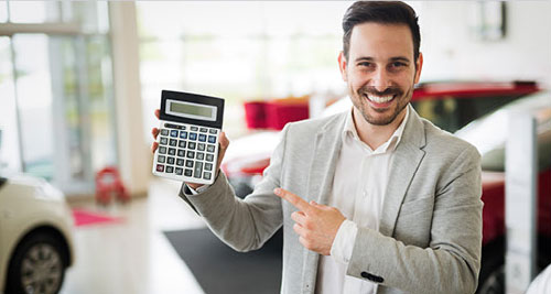 dealership finance specialist holding calculator for auto loan payment estimate