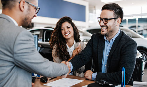 customers shaking hands with dealership finance manager after vehicle purchase