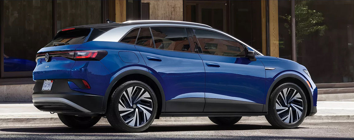 blue Volkswagen ID4 electric SUV parked outside modern building side profile