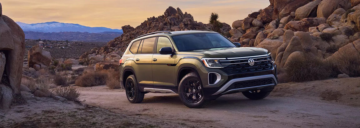 Volkswagen Atlas SUV driving on rocky desert terrain at sunset
