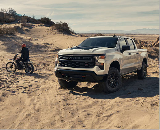 Chevrolet Silverado Trail Boss parked on sandy terrain, emphasizing off-road engineering, all-terrain confidence, and outdoor recreation versatility