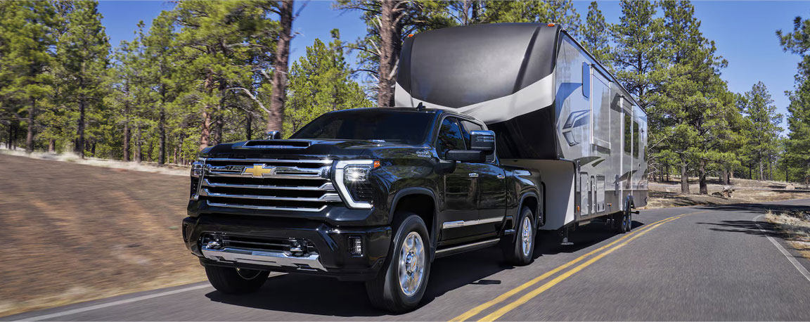 Chevrolet Silverado HD towing a large fifth-wheel RV, featuring long-distance towing capability, recreational versatility, and heavy-duty truck performance