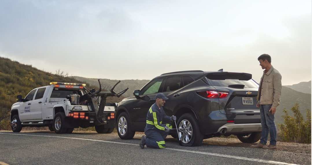 Roadside assistance technician changing a tire on a Chevrolet SUV during a breakdown