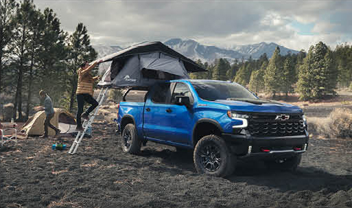Blue Chevrolet Silverado with rooftop tent set up for outdoor camping
