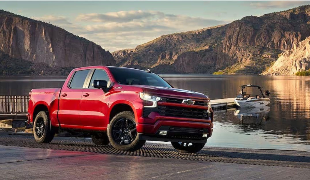 Red Chevrolet Silverado parked by a lake near a boat dock