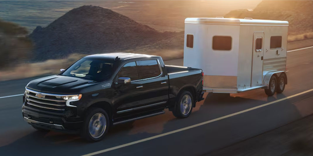 Black Chevrolet Silverado towing an enclosed trailer on an open highway