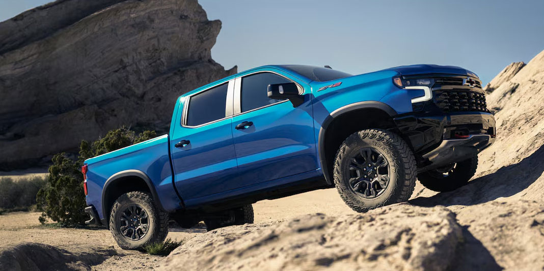 Blue Chevrolet Silverado ZR2 driving off-road on rocky desert terrain